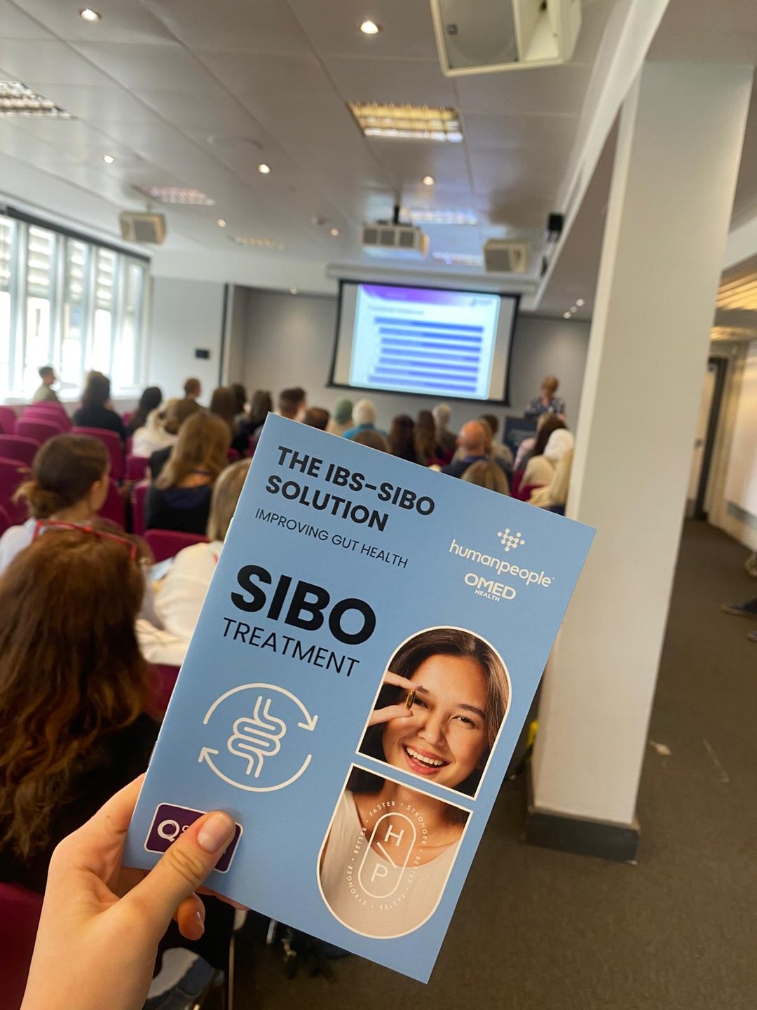 humanpeople and OMED Health SIBO leaflet held up in a congress session